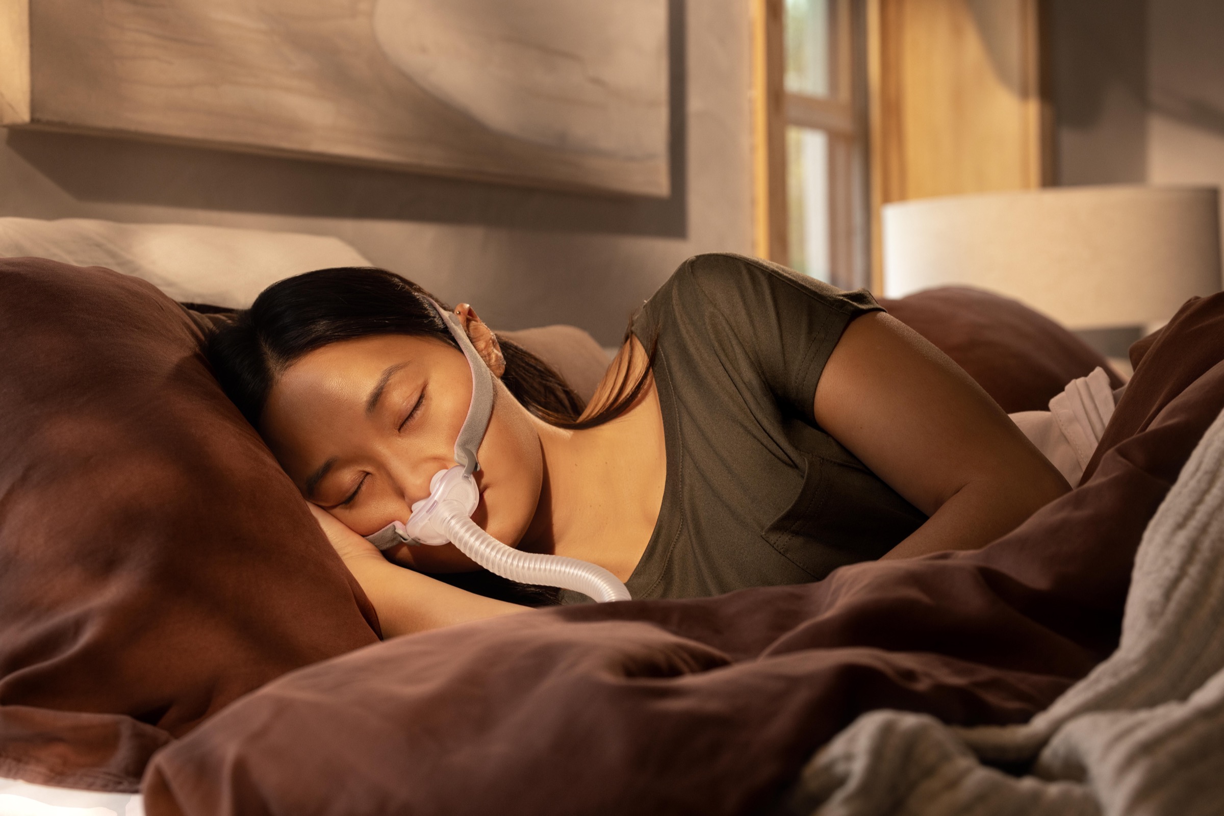 A woman sleeping restfully wearing a nasal-pillow CPAP mask